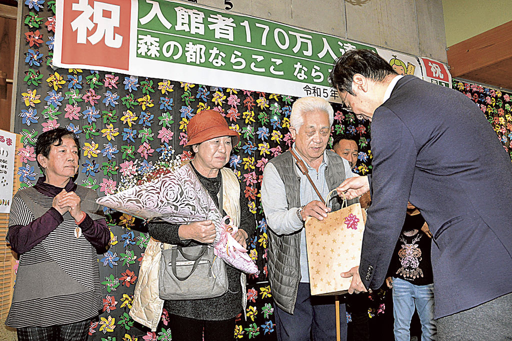 花束と記念品を受ける伊藤春男さん（左から３人目）、広子さん（同２人目）夫妻＝掛川市居尻のならここの湯