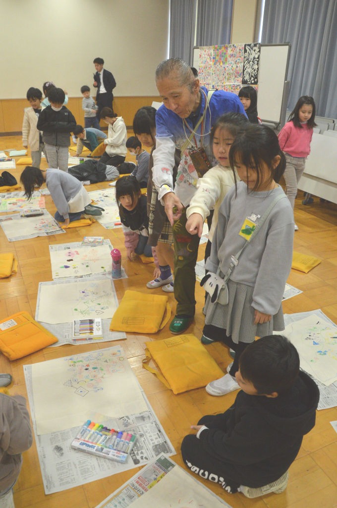 ワークショップで児童が描いた作品を見て回る本田さん＝沼津市の第四小