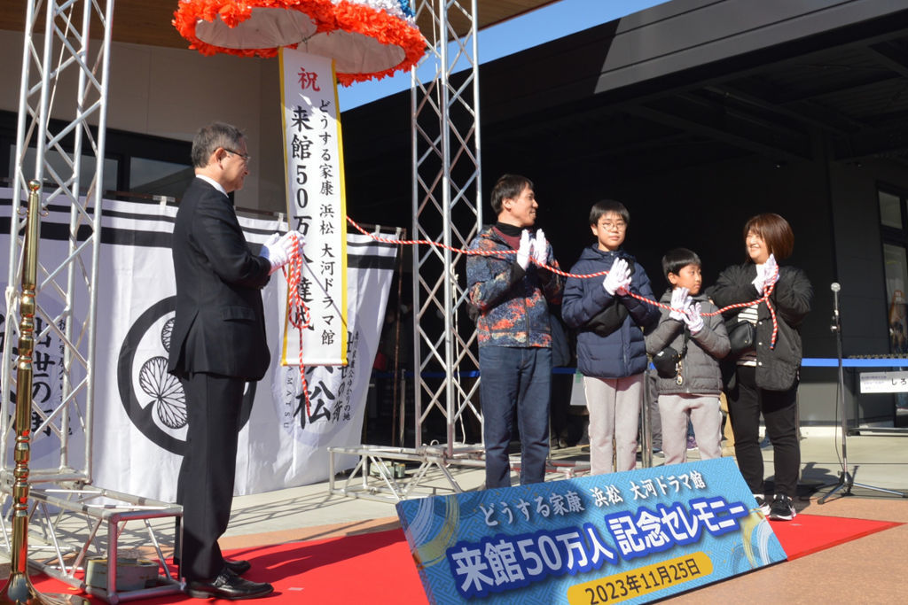 中野浜松市長（左）とくす玉を割る松立幸大君（右から３人目）と家族＝同市中区の「どうする家康　浜松　大河ドラマ館」