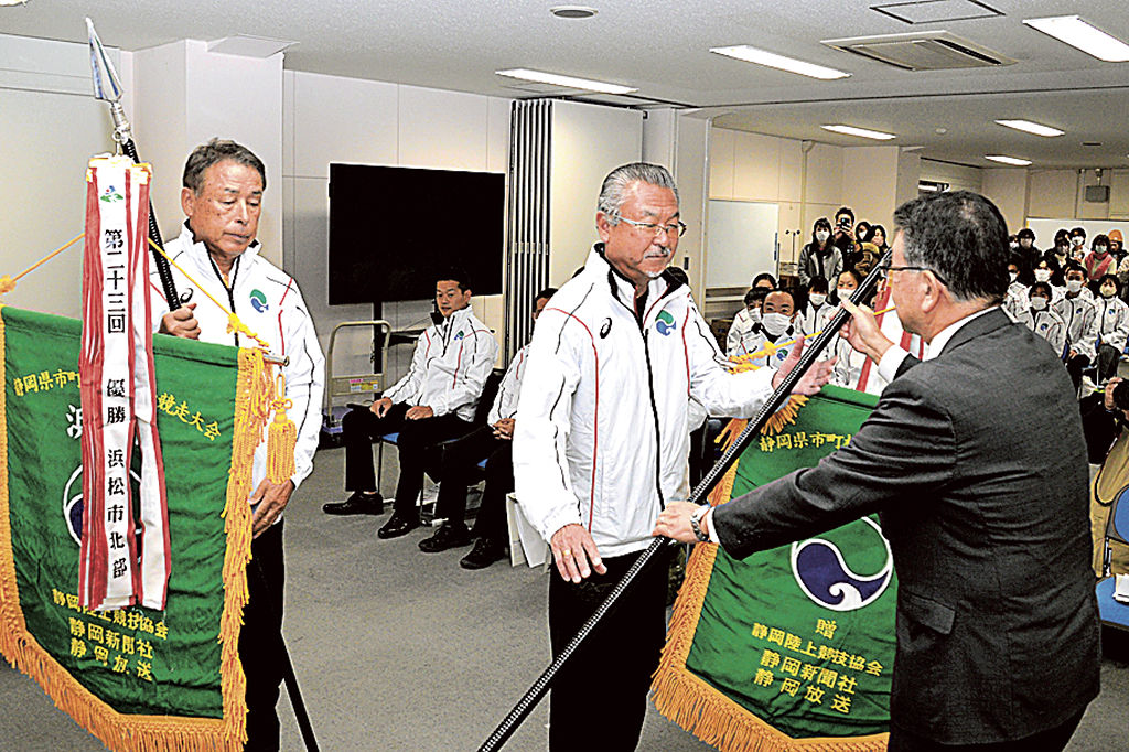 山名副市長（右）から代表旗を受け取る北部、南部両チームの監督＝浜松市役所