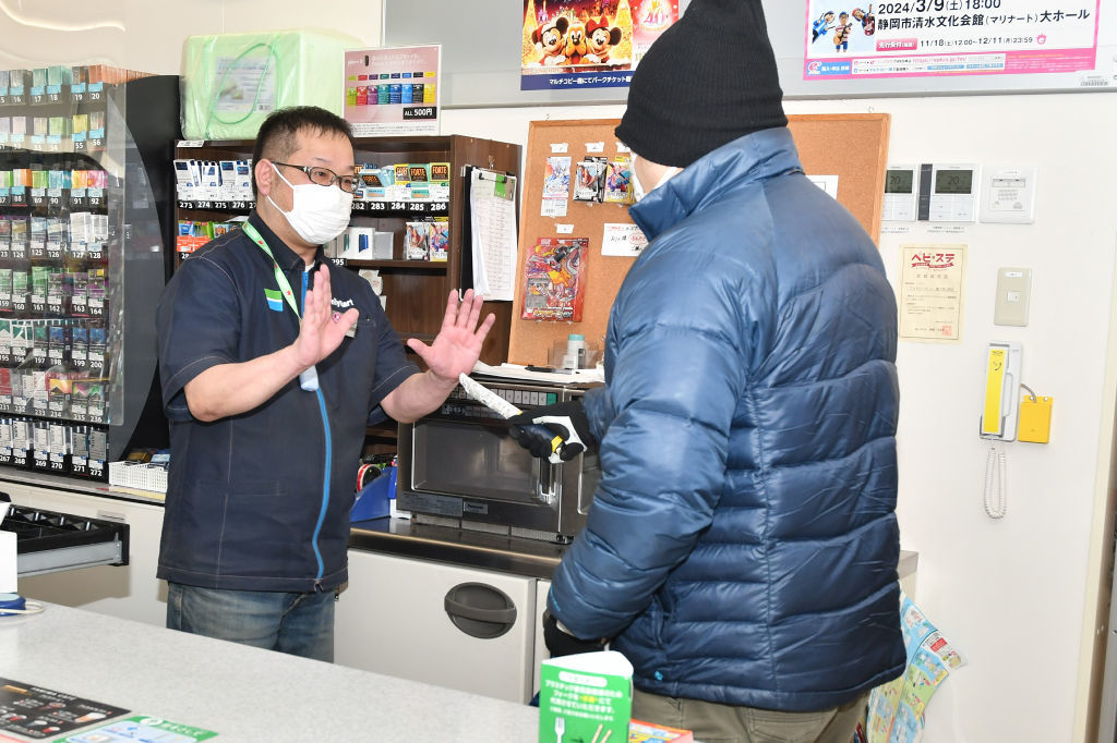 強盗犯役の男に対応する店員＝富士宮市のファミリーマート富士宮山宮店