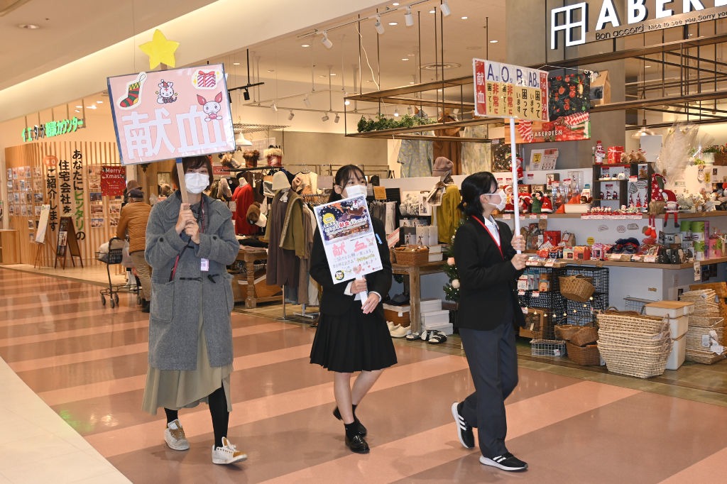 プラカードを掲げて献血への協力を呼びかける学生＝静岡市駿河区