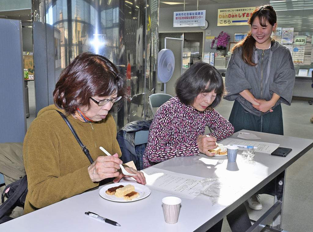 白石さん（右）の説明を聞きながら海老芋を使ったチーズケーキを試食する来場者＝静岡市駿河区の「みなくる」
