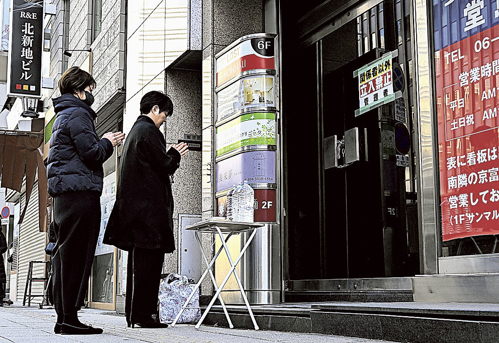 大阪・北新地の放火から２年。ビルの前でお経を読む西沢弘太郎院長の妹伸子さん（右）＝１７日午前