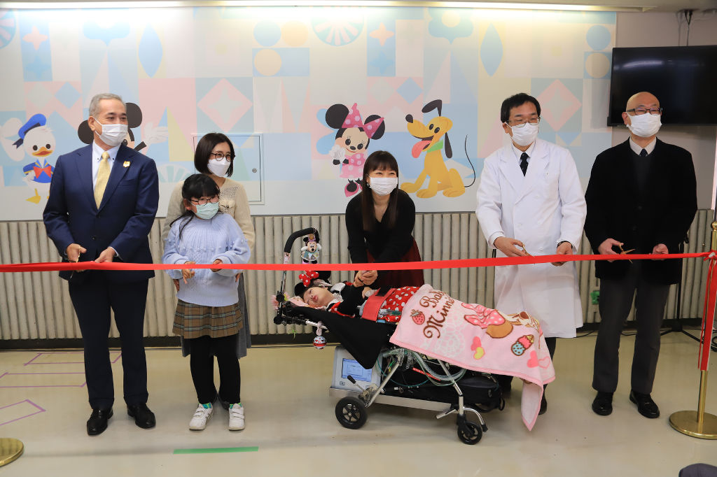 壁紙の完成を祝い、患者家族とテープカットを行う関係者＝静岡市葵区の県立こども病院