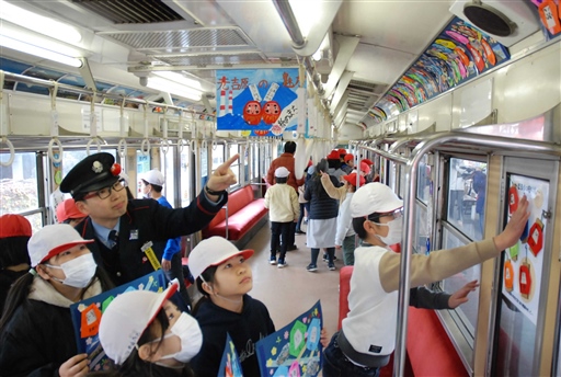 だるまをＰＲするため電車内を飾り付ける児童ら＝富士市の岳鉄吉原駅（写真の一部を加工しています）