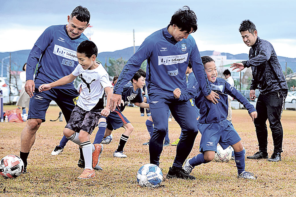 児童にサッカー指導を行う選手ら＝沼津市の明電舎グラウンド（写真の一部を加工しています）