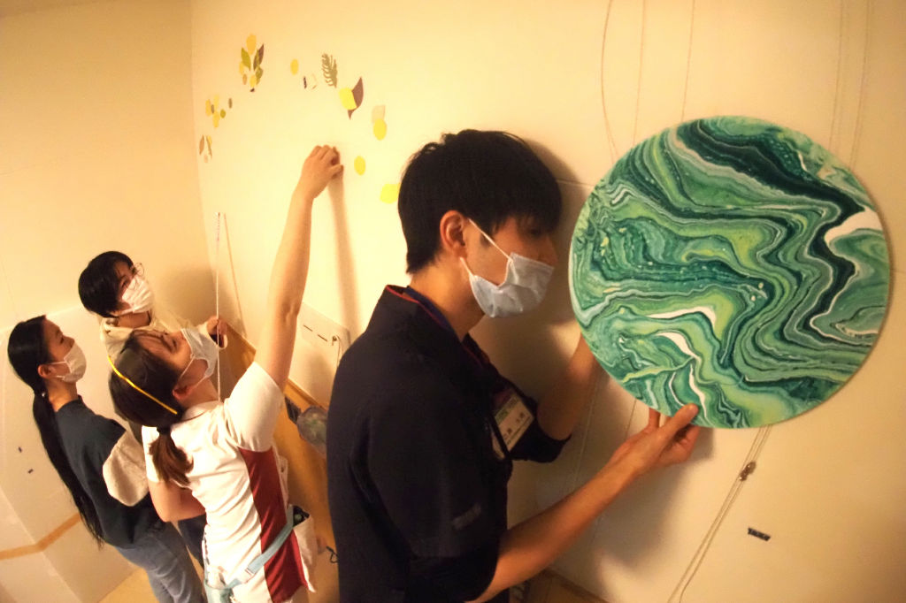 陣痛室の壁に作品を飾りつける学生や職員＝磐田市大久保の市立総合病院