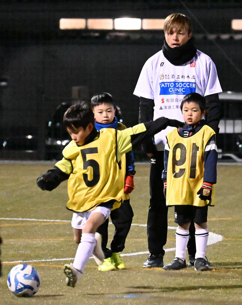 遠藤選手（右奥）から指導を受ける子どもたち＝浜松市浜北区の浜北平口サッカー場