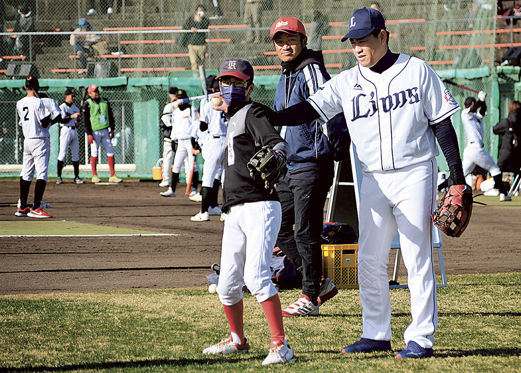 牧田さん（手前右）から投球フォームの指導を受ける参加者＝磐田市見付の磐田城山球場