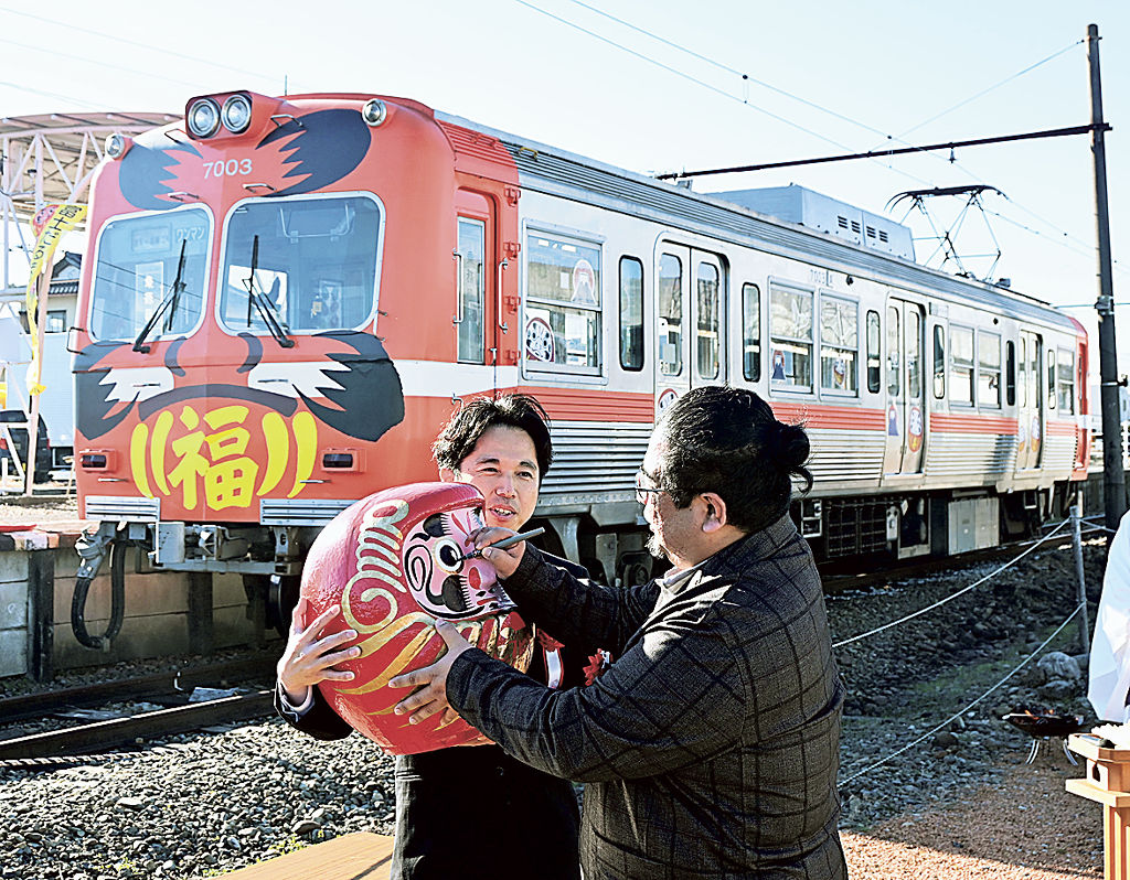 「だるま電車」の前で安全祈願する関係者＝富士市の岳南江尾駅