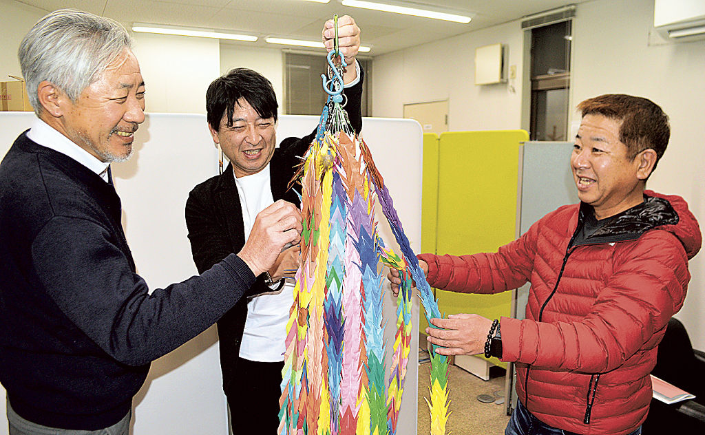 苦労して作った千羽鶴の出来を確かめるメンバー。チームメンバーのようにそれぞれ個性のある折り鶴が集まった＝２０２３年１２月中旬、静岡市葵区