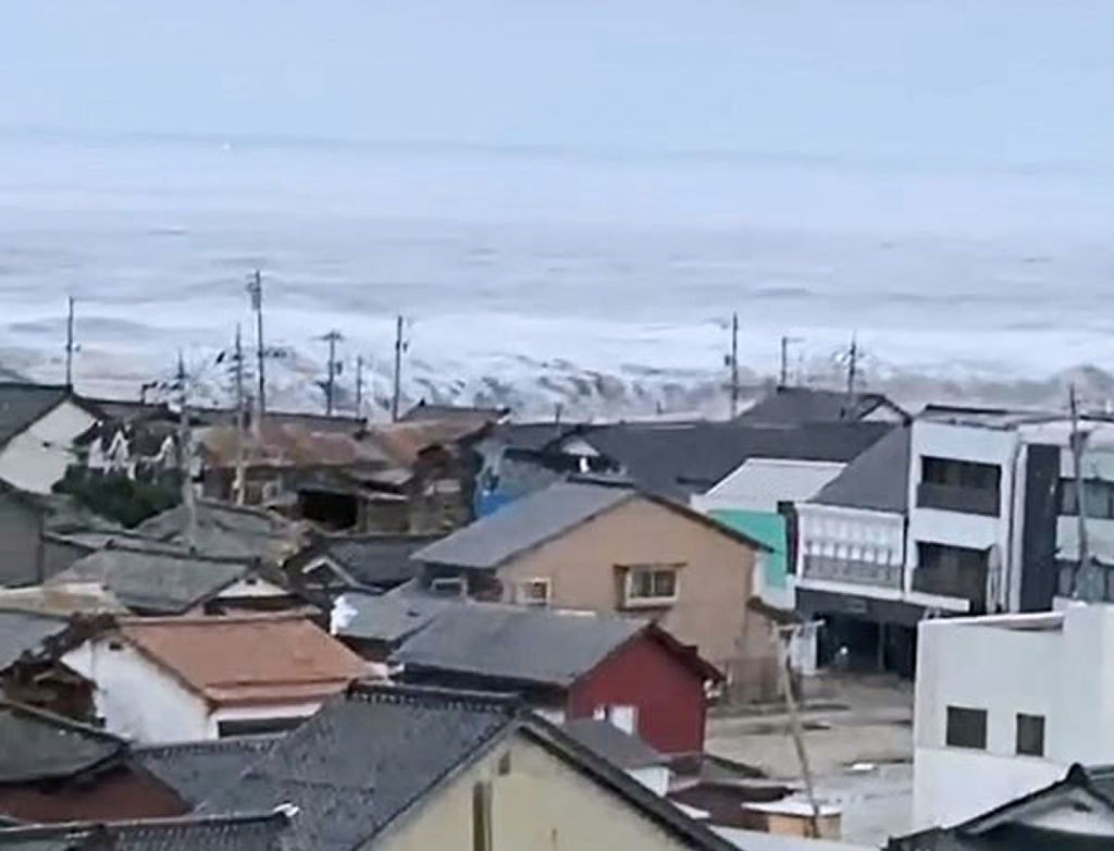 堤防を乗り越えて石川県珠洲市街に迫る津波＝１日（住民提供）