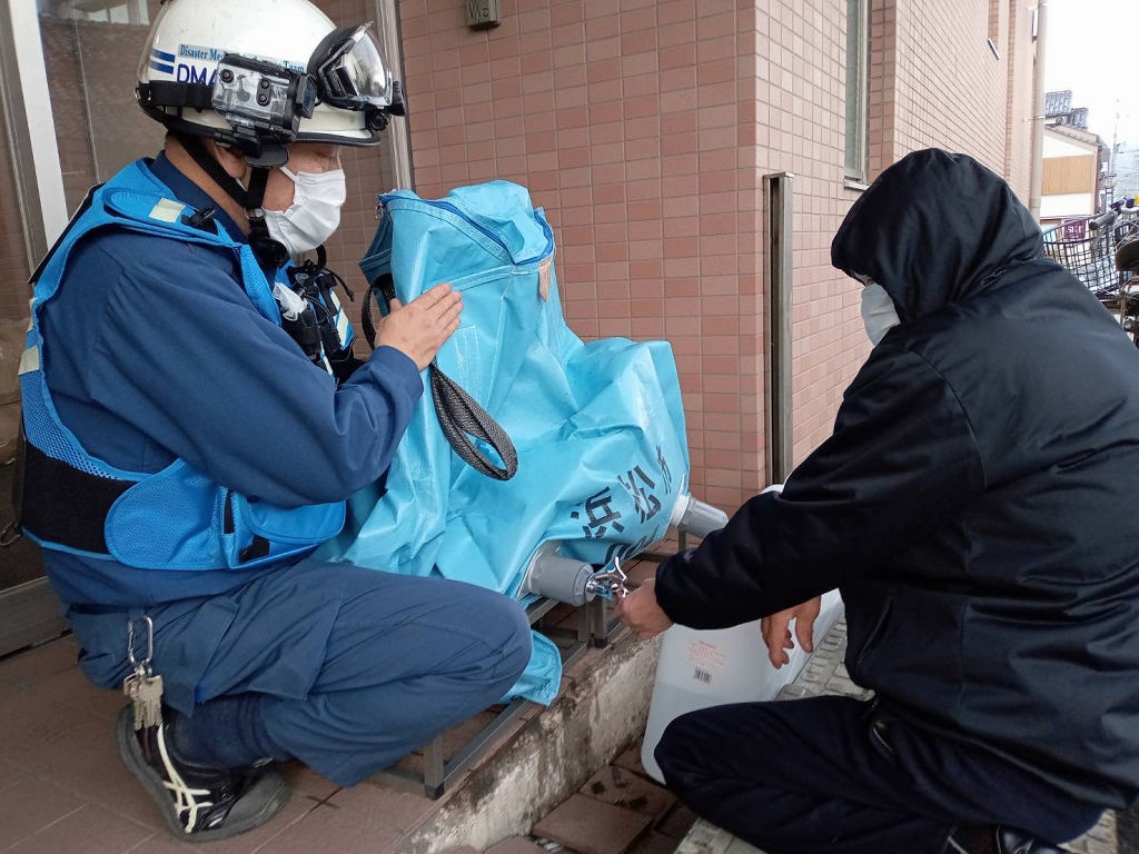 給水作業を手伝う山本さん（左）＝６日午後、石川県輪島市