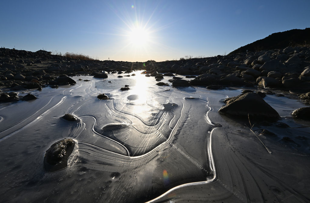 氷点下となった厳しい冷え込みの朝、藁科川の河原の水たまりが凍り朝日に照らされた＝１４日午前７時５５分、静岡市葵区（写真部・久保田竜平）