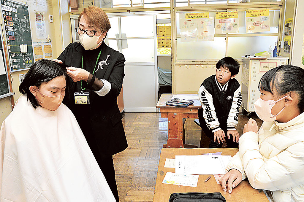 内藤さん（左から２人目）のヘアアレンジを見守る児童＝静岡市葵区の服織西小