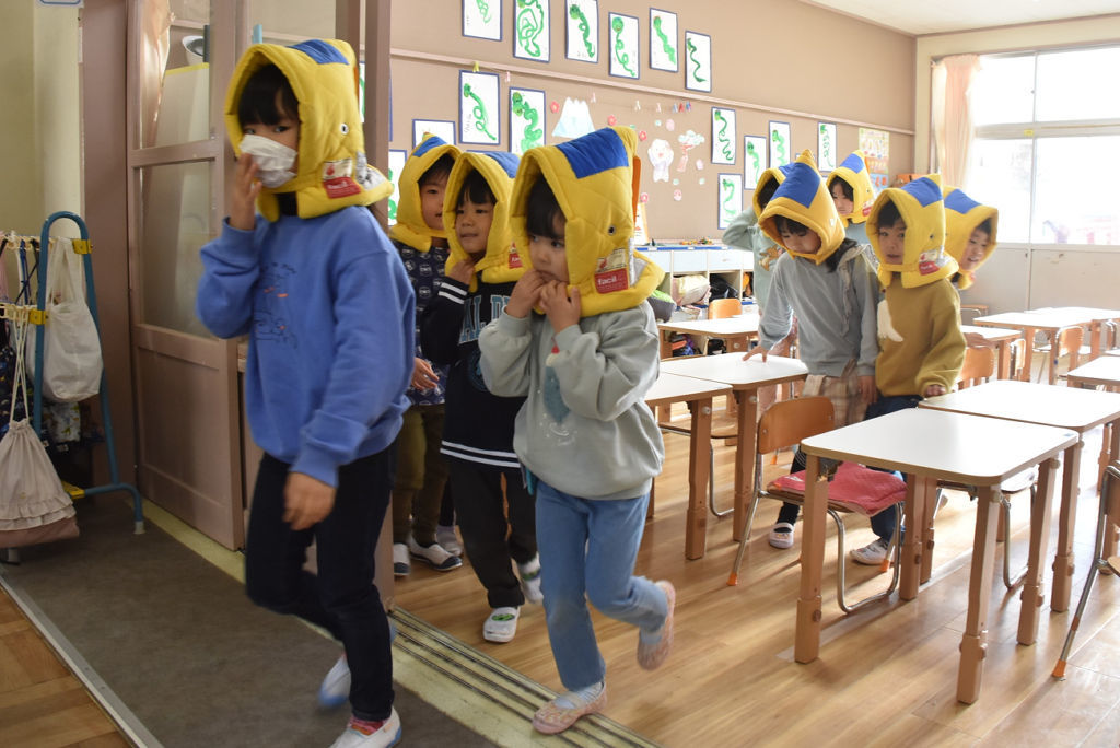 防災頭巾をかぶり避難する園児＝三島市の徳倉幼稚園