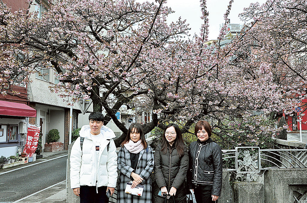 桜を背に記念撮影する参加者。中国人客の本格回復を見据えて地域の魅力を伝えた＝熱海市