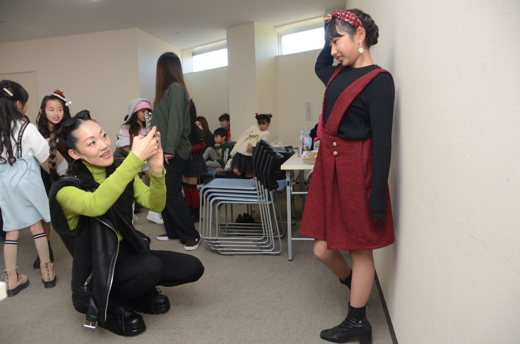 ファッションモデル体験に臨む子どもを撮影する吉田愛菜さん＝１２月上旬、浜松市浜名区