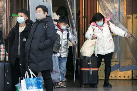 北京駅から出てくるマスク姿の人たち＝２６日（共同）