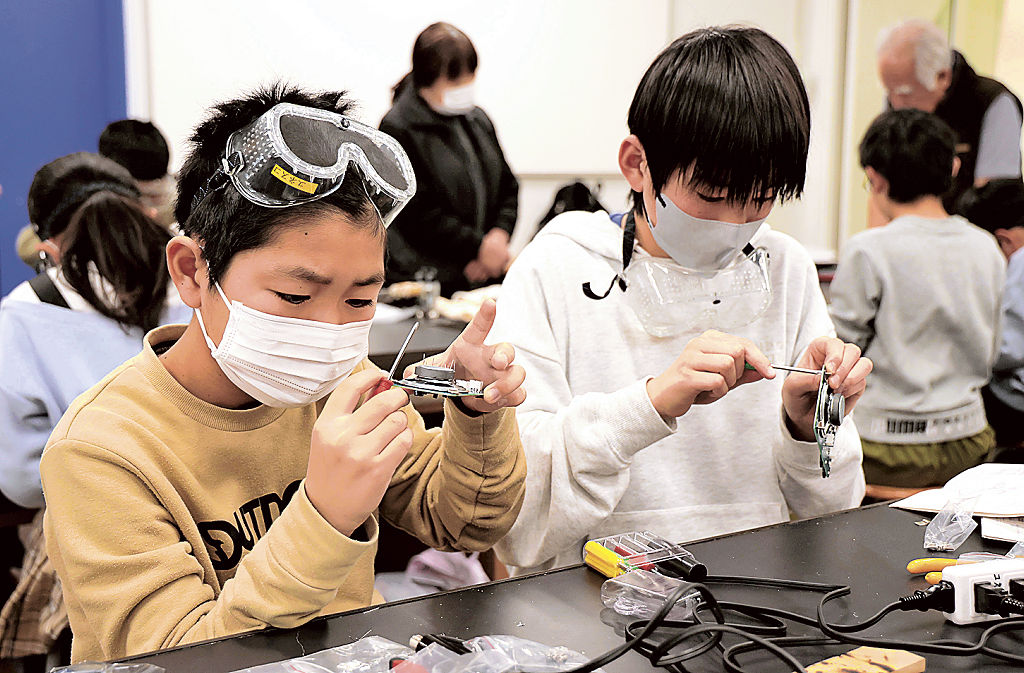 真剣な表情でラジオを組み立てる参加児童＝浜松市中央区の浜松科学館