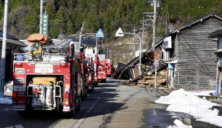 倒壊した建物の前を通行する消防車＝２日、石川県輪島市
