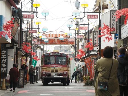 昭和の町の商店街を走るレトロなボンネットバス。懐かしい姿に観光客がカメラを向ける＝大分県豊後高田市