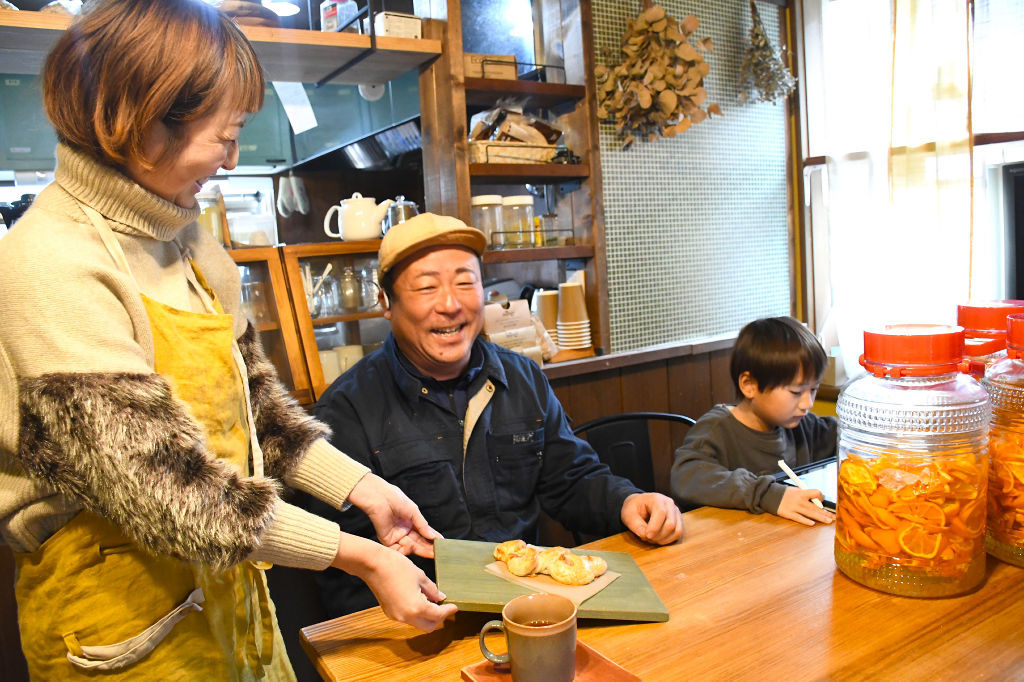 宿泊客の永坂敏泰さん（中央）に朝食を提供する久米ゆきさん（左）。共有スペースでは久米さんの長男もくつろぐ＝２４日、浜松市浜名区三ケ日町のｃｏｃｏ－Ｒｉｎ