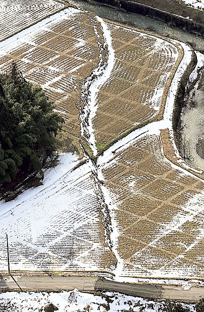 石川県珠洲市若山町の水田を横切るように現れた崖。高低差ができた部分に雪がたまっていた＝３１日午後（共同通信社ヘリから）
