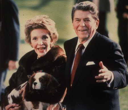 １９８６年１２月、ホワイトハウスで、愛犬を抱えた妻ナンシー氏と歩くレーガン氏（ＡＰ＝共同）
