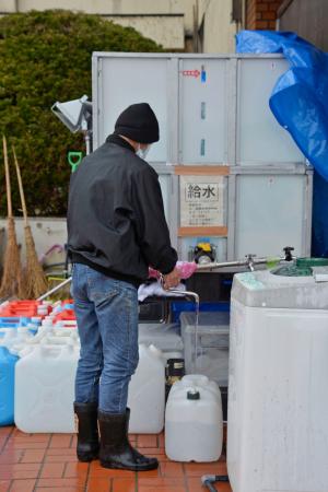 避難所でポリタンクに水をくむ避難者の男性＝１日午後、石川県珠洲市