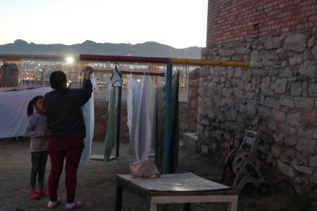 米エルパソのシェルターで洗濯物を干す女性ら。目と鼻の先に米国とメキシコの国境の壁がある＝２０２３年１２月（共同）