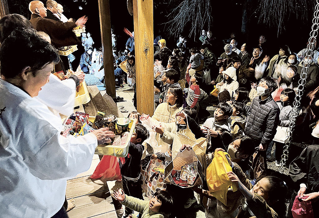 菓子を集めようと手を伸ばす子どもたち＝富士宮市の興徳寺