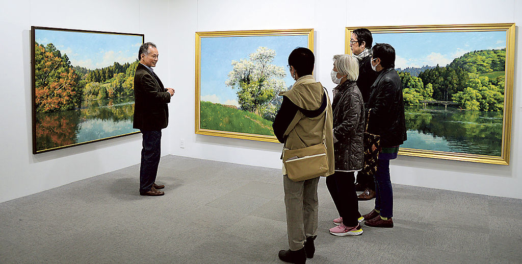 里山の自然風景を写実表現で追求した西谷さん（左）の個展＝藤枝市のアートカゲヤマ画廊