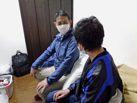 精神障害と発達障害のある男性（手前）が暮らす部屋で相談に乗る訪問看護師の山田祥和さん＝２０２３年１１月、神奈川県内