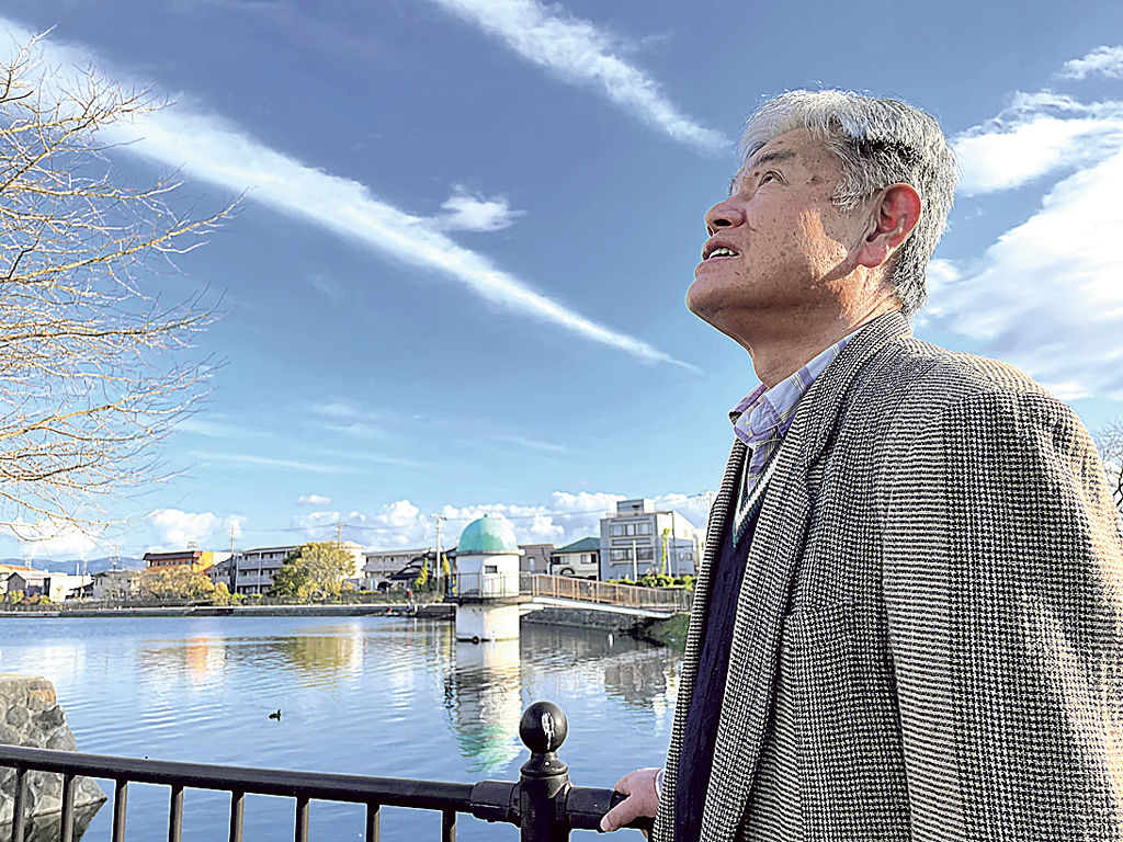 竜の形をした雲を見つめる門池地区連合自治会長の福田和男さん＝２０２３年１２月、沼津市岡一色の門池公園