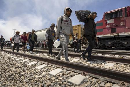 ２０２３年５月、メキシコ・シウダフアレス近郊で、貨物列車を降り米国との国境に向かう移民（ゲッティ＝共同）