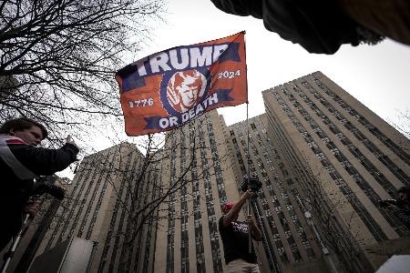 ２０２３年４月、ニューヨーク市マンハッタンの裁判所の外で旗を振るトランプ前米大統領の支持者（ゲッティ＝共同）