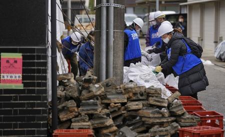 石川県七尾市のしょうゆ店で、外壁の破片を片付けるボランティア＝１月２７日午後