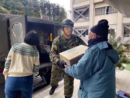 石川県珠洲市立緑丘中で、震災後初めて陸上自衛隊の隊員から物資を受け取る避難者ら＝２月５日午前