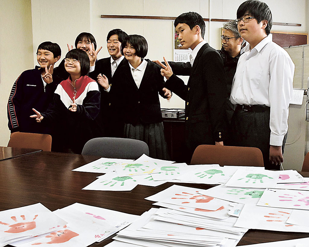集めた手形を前にして記念写真に収まる小野生徒会長（左から４人目）と竹山さん（同５人目）＝三島市立南中
