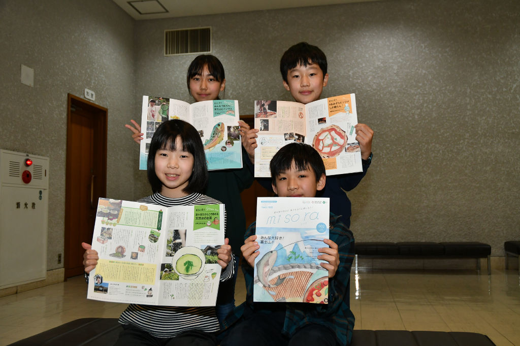 完成した冊子をお披露目する小中学生＝富士宮市の市民文化会館