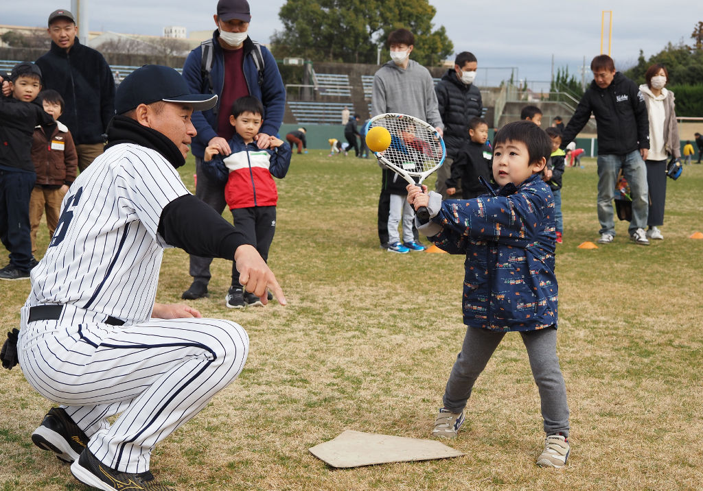 高田さんの（左）手ほどきでバッティングに挑戦する子ども＝磐田市見付の磐田城山球場