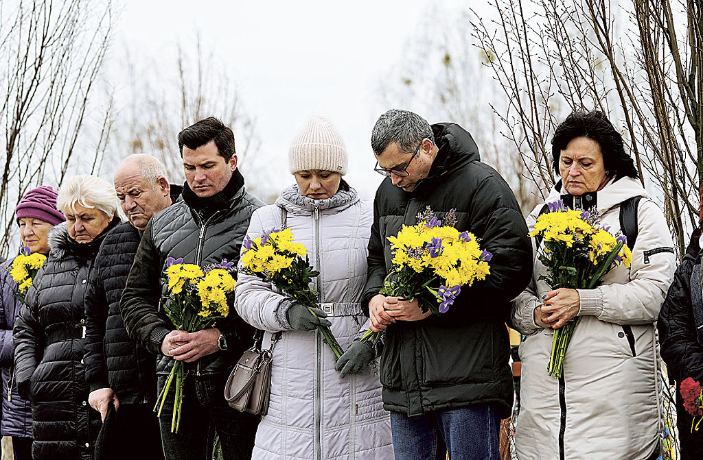 ロシアのウクライナ侵攻開始から２年となり、キーウ近郊ブチャで開かれた追悼式で黙とうする遺族ら＝２４日（共同）