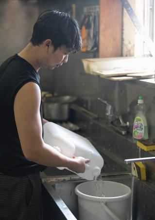 石川県能登町・小木港の寮で、食器を洗うためにバケツに水をためるインドネシア人漁業実習生のシコ・サンジャヤさん＝１４日