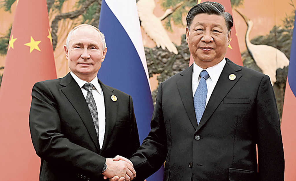 会談で握手するロシアのプーチン大統領（左）と中国の習近平国家主席＝２０２３年１０月、北京の人民大会堂（タス＝共同）