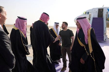 ２７日、サウジアラビアの空港で迎えられるウクライナのゼレンスキー大統領（奥中央右）（ロイター＝共同）