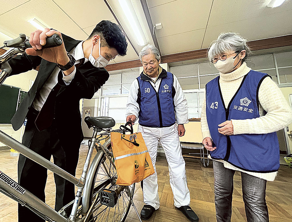 自転車のヘルメット専用横断バッグの活用方法を紹介する署員＝静岡市駿河区