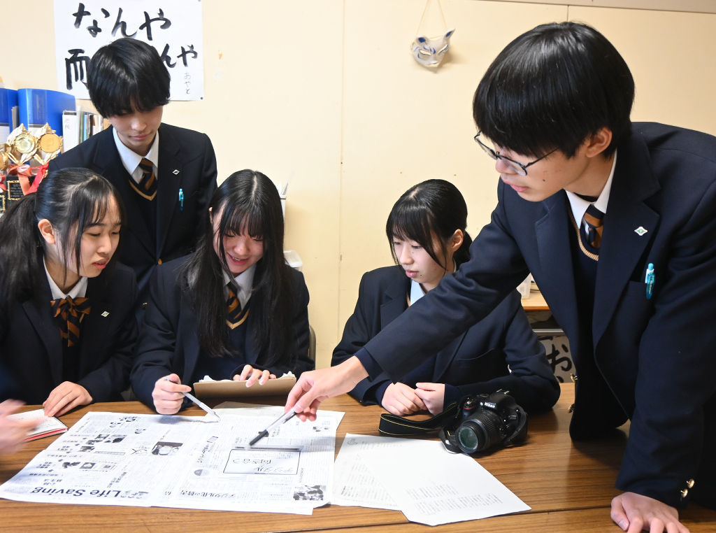 制作した新聞を並べて企画について話し合う部員たち＝富士市の富士東高