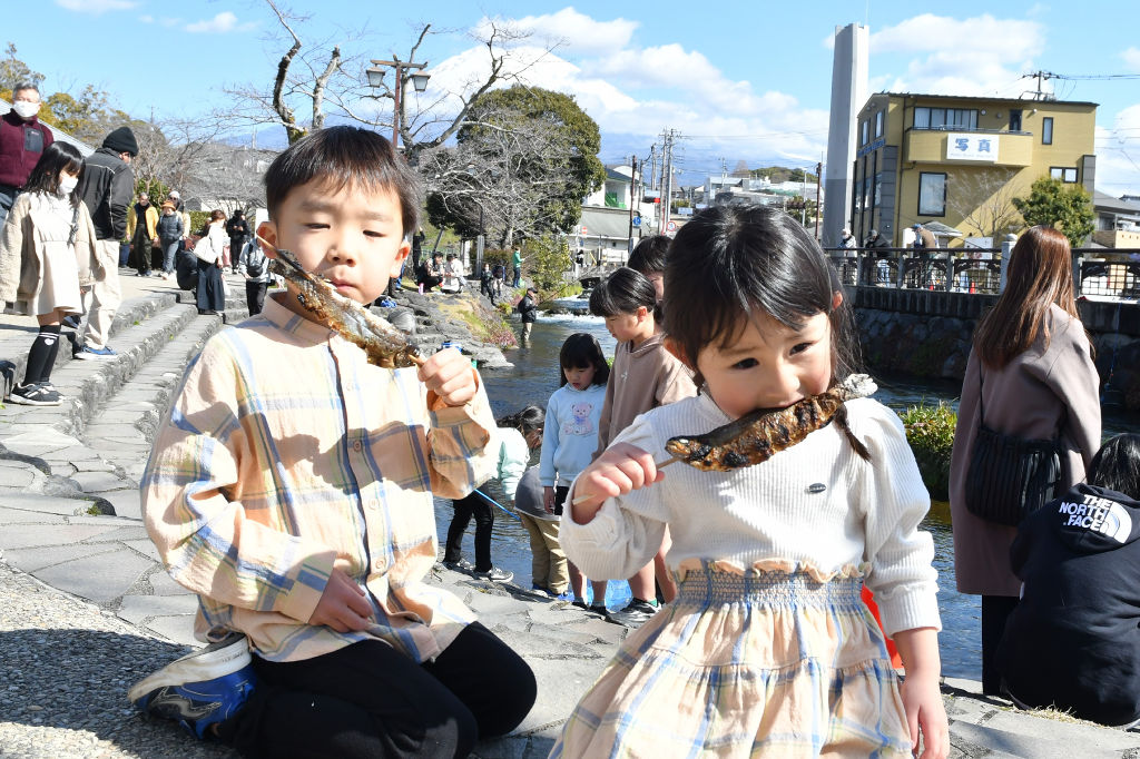 ニジマスの塩焼きを食べるきょうだい＝富士宮市の神田川ふれあい広場